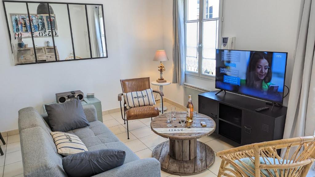 un salon avec un canapé et une télévision à écran plat dans l'établissement Maison BARBADINE, à Saint-Denis-dʼOléron