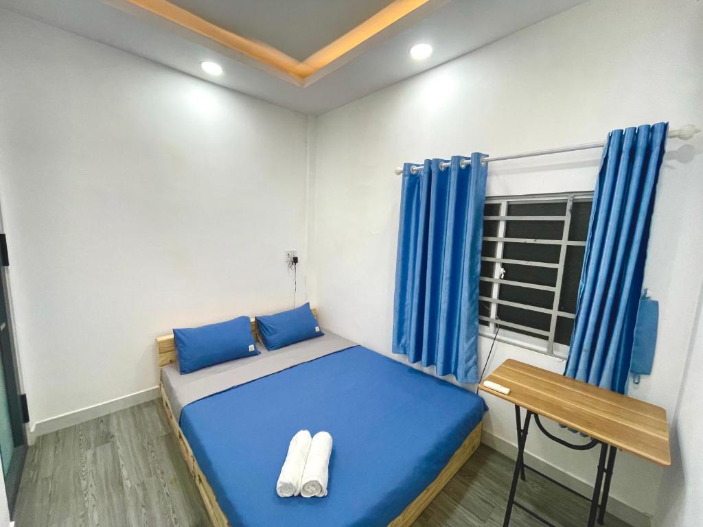 Cette petite chambre comprend un lit bleu et une table. dans l'établissement Enjoy Homestay, à Hô-Chi-Minh-Ville
