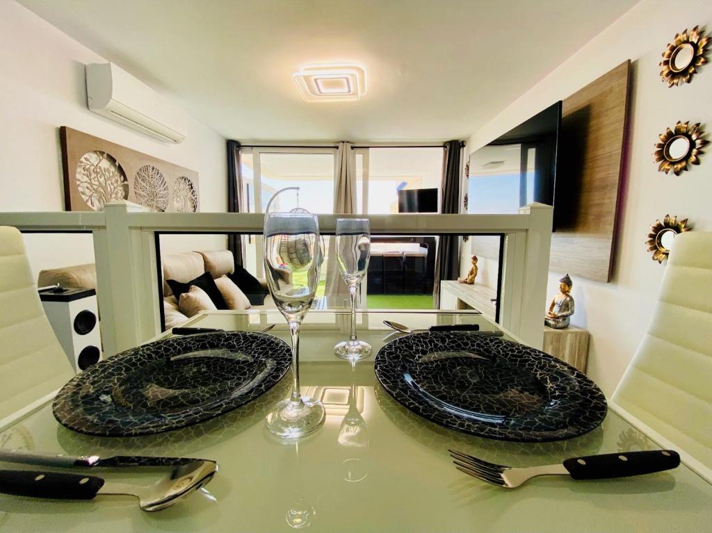 stół z 2 talerzami i kieliszek wina w obiekcie Luxury apartment in playa del inglés w mieście San Bartolomé