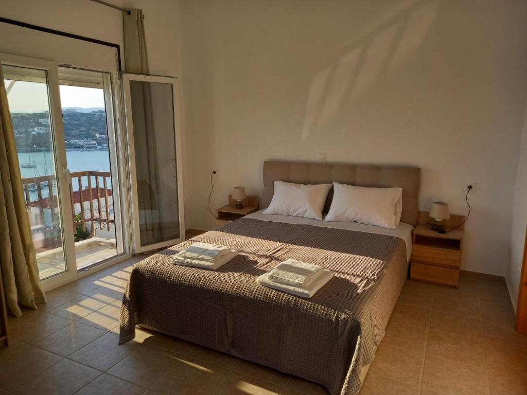 ein Schlafzimmer mit einem Bett und einem großen Fenster in der Unterkunft AMPELOS ANDROS in Batsi