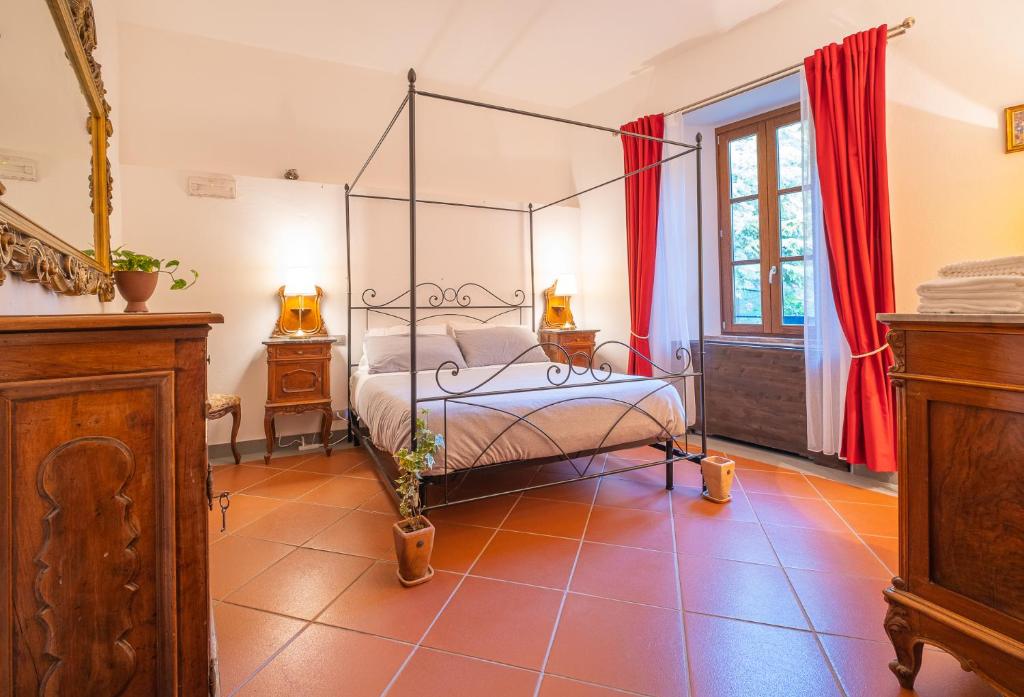 a bedroom with a canopy bed and red curtains at Veleia Romana B&B in Rustigazzo