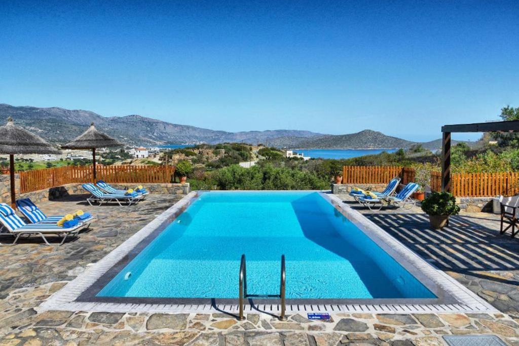 a pool with chairs and a view of the ocean at Villa Glan Y Mor in Elounda