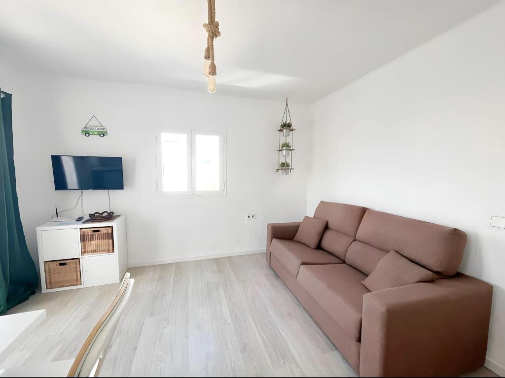 sala de estar con sofá y TV en Apartamentos Formentera Copacabana 18, en Es Pujols