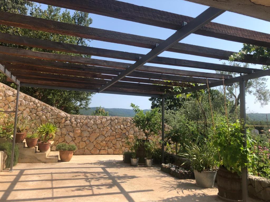 a wooden pergola with potted plants and a stone wall at Apartment Lena in Čižići