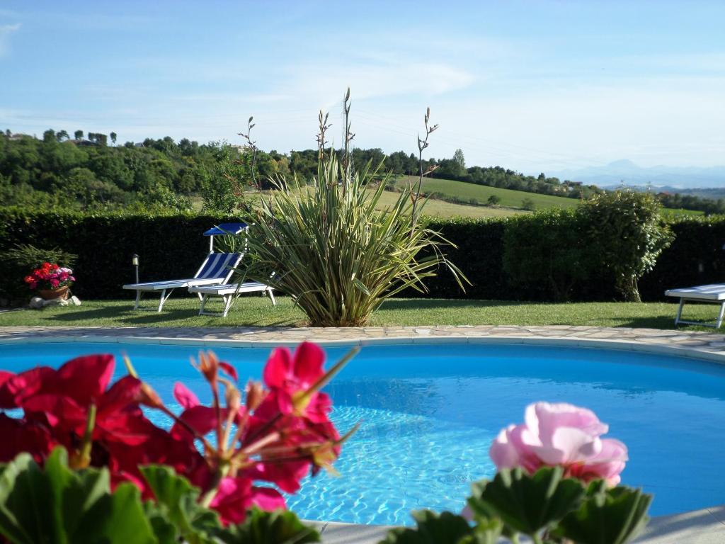 a blue swimming pool with a chair and flowers at Bed and Breakfast " Il Tesoro di Mario " in Falconara Marittima