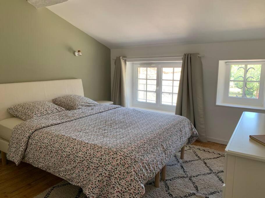ein Schlafzimmer mit einem Bett und zwei Fenstern in der Unterkunft La Saintonge in Saint-Sulpice-dʼArnoult