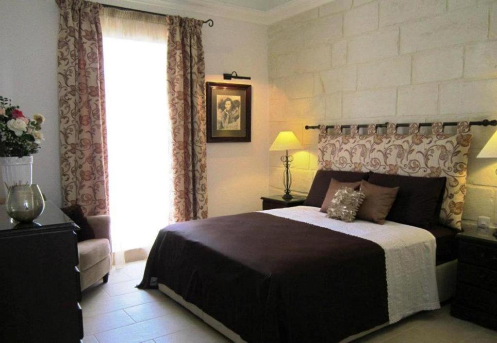 um quarto com uma cama grande e uma janela em Townhouse Twenty em Żebbuġ