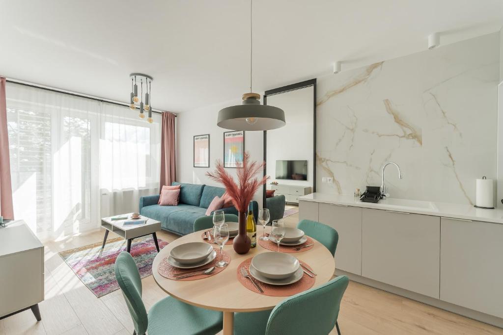 a kitchen and living room with a table and chairs at Sunset Vibes Apartment in Kołobrzeg
