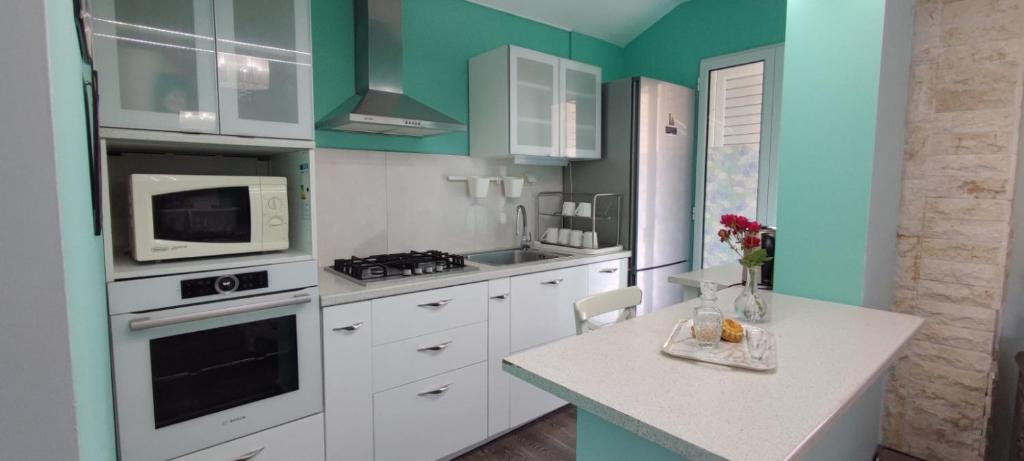 a kitchen with white cabinets and green walls at MarilidiaHouse in Kardhoulianós