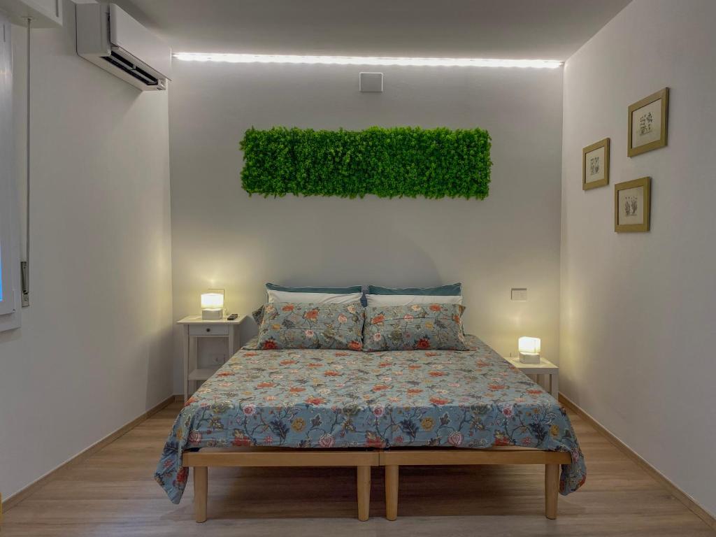 een slaapkamer met een bed en een groene plant aan de muur bij Il giardino dei portici in Medicina
