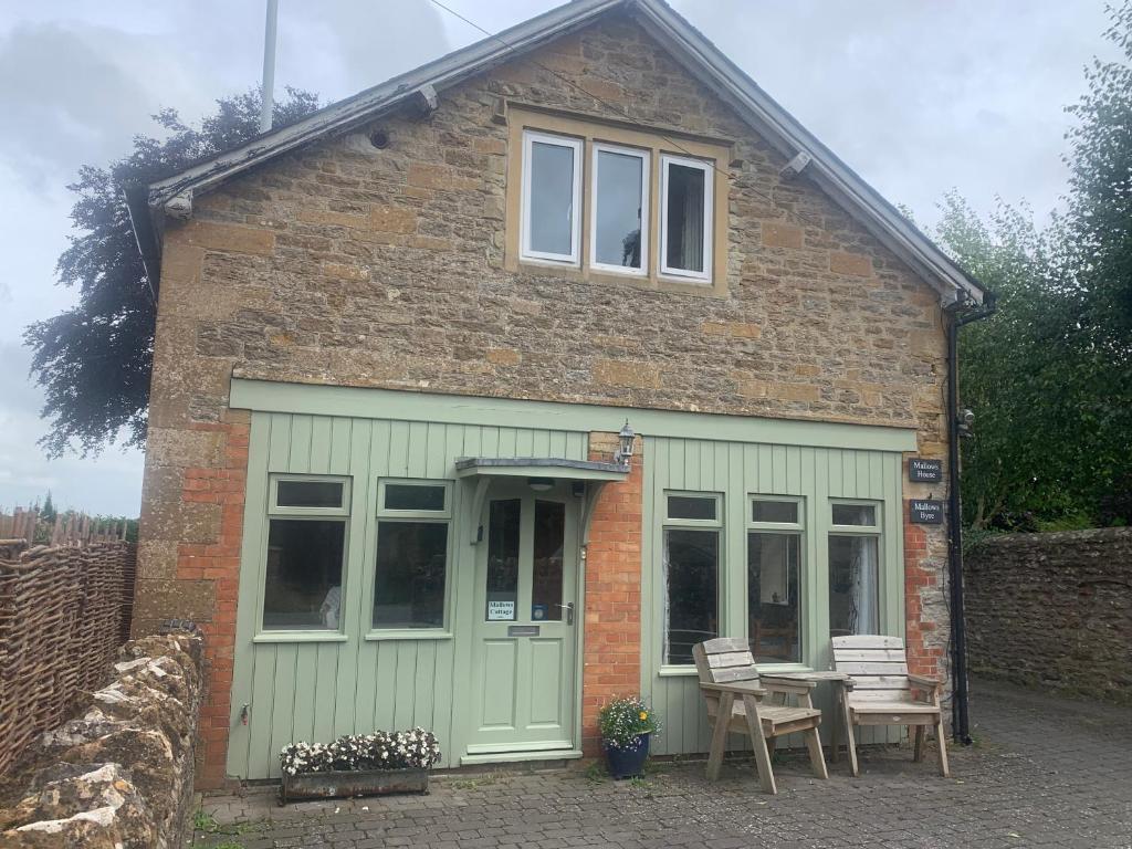 a house with a table and chairs in front of it at Mallows Cottage in Sherborne