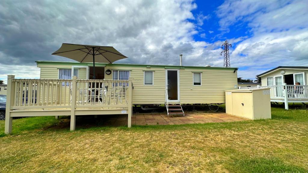 a yellow house with a deck and an umbrella at Holiday Freedom in Clacton-on-Sea