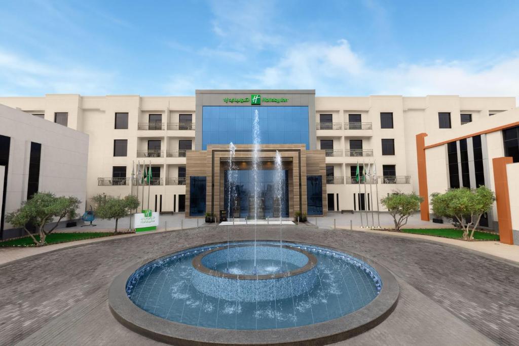 Holiday Inn Riyadh The Business District, an IHG Hotel في الرياض: مبنى فيه نافورة امام مبنى