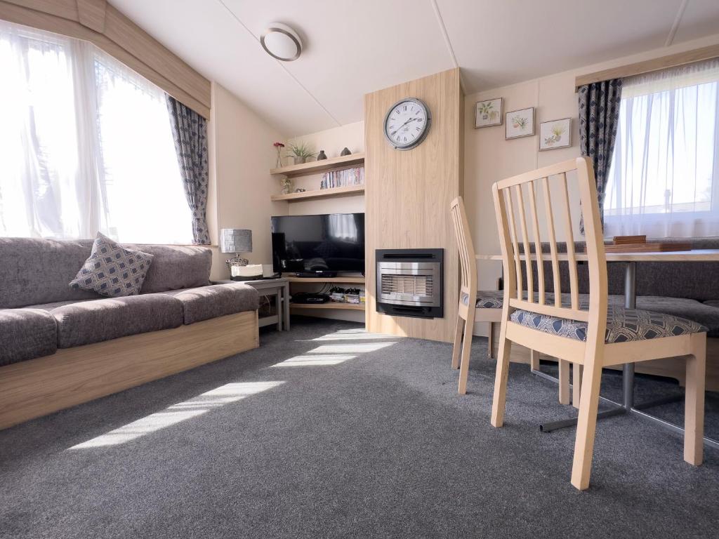 a living room with a couch and a table and a clock at Edinburgh - Seton Sands-Salsa Caravan-Pet Friendly in Port Seton