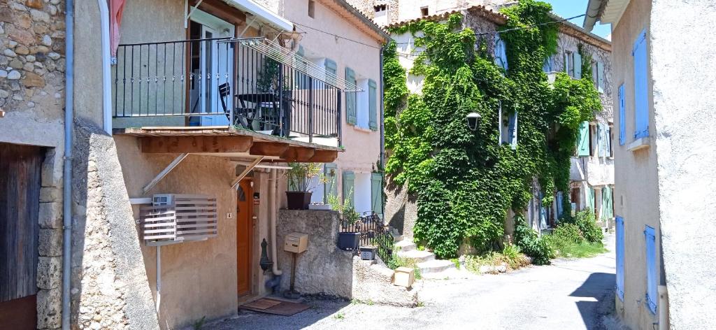 Une allée avec des bâtiments, un balcon et des vignes dans l'établissement Maison de village en Provence, à Puimoisson