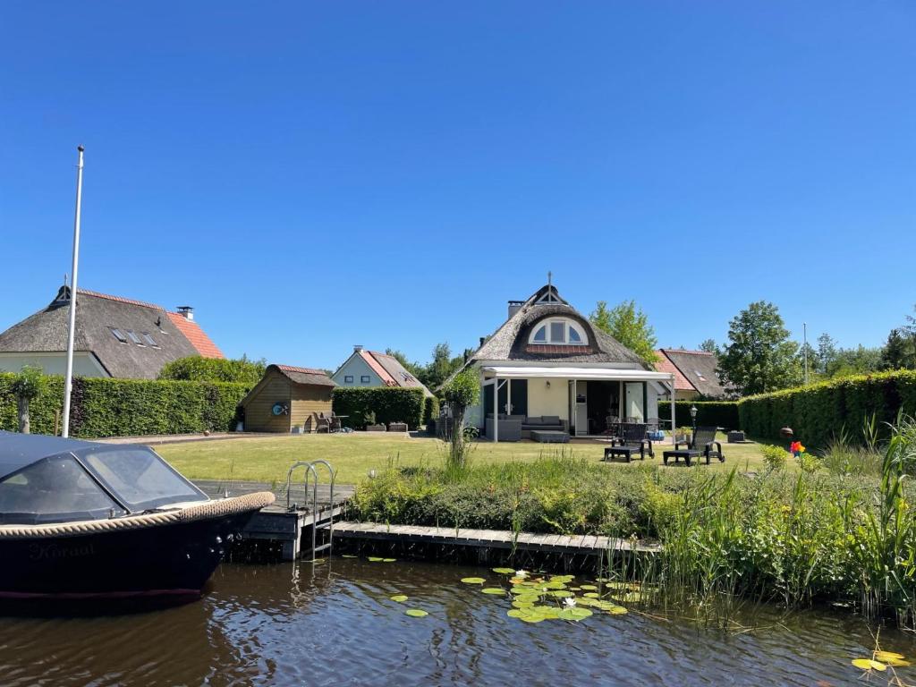 a house with a boat on the water in front at Vakantiehuis aan het water in Friesland in De Rijlst