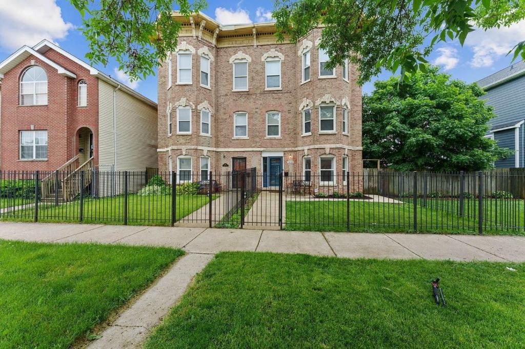 a building with a fence in front of a yard at Spacious Row Home next Transit near Downtown w Parking in Chicago