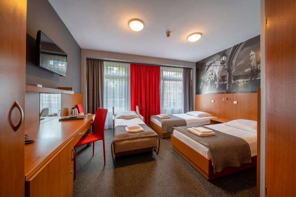 a hotel room with two beds and a desk at Hotel Alexander in Krakow