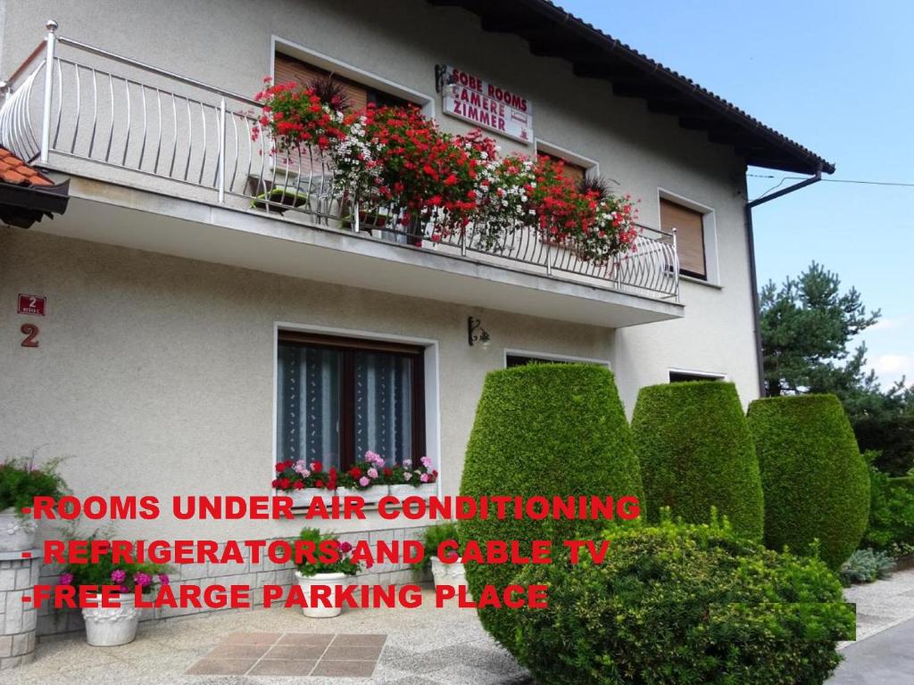 a building with a balcony with flowers on it at Rooms Kapelj in Postojna