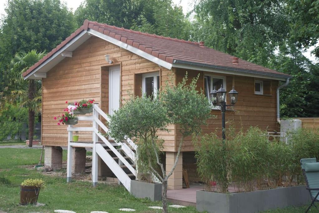 Cette petite maison en bois dispose d'une terrasse couverte et d'un escalier. dans l'établissement Au Bord de l'Oise, à Auvers-sur-Oise