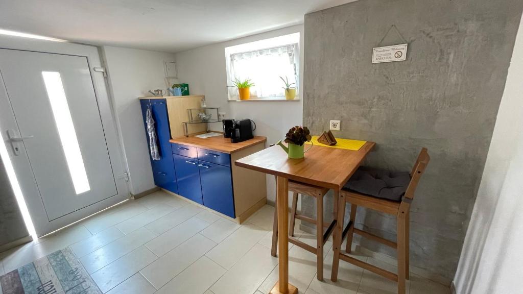 una pequeña cocina con una mesa de madera y armarios azules en Gemütliche möblierte Souterrain Wohnung, en Hannover