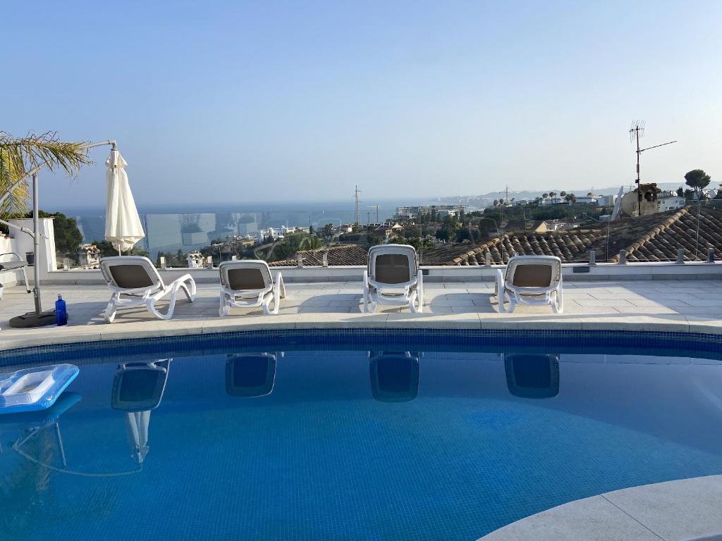 un grupo de sillas y una piscina en 2 bedrooms villa with sea view private pool and furnished terrace at Benalmadena 2 km away from the beach, en Benalmádena
