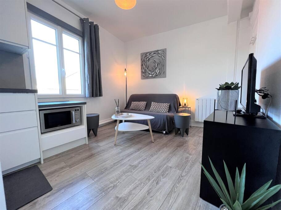 un salon avec un canapé et une table dans l'établissement Le Cyrano, Deauville - App. T2 proche de la mer, à Deauville