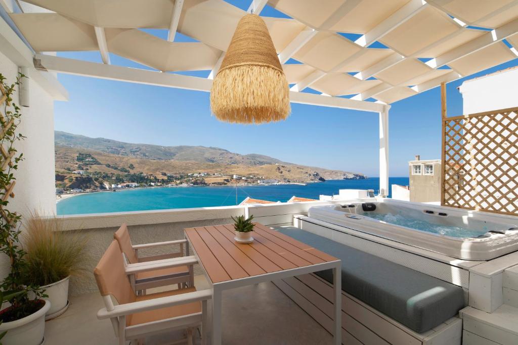 a patio with a jacuzzi tub and a table at ISTION ANDROS LUXURY SUITES in Andros