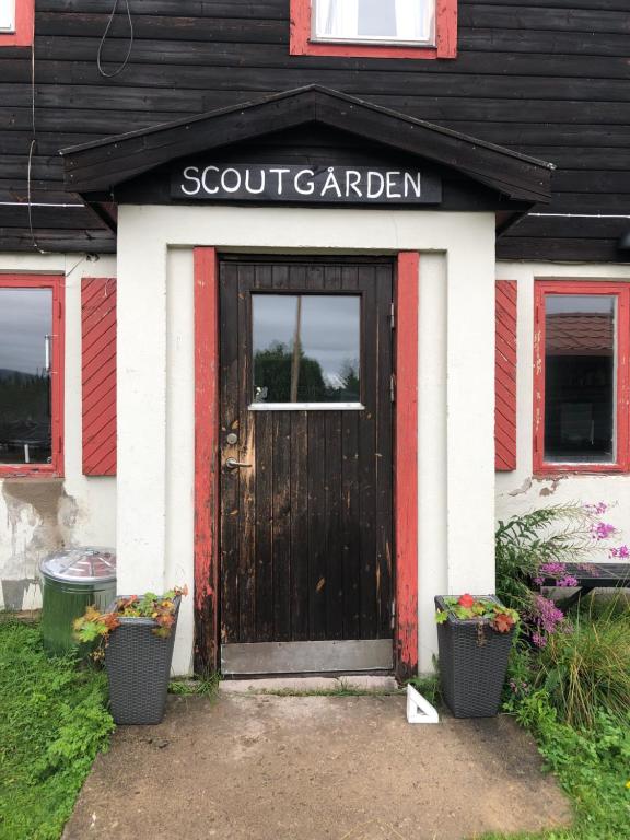 een voordeur van een huis met een bord met een Schotse tuin bij Fjällgården Grövelsjön Vandrarhemsrum Töfsingdalen in Idre