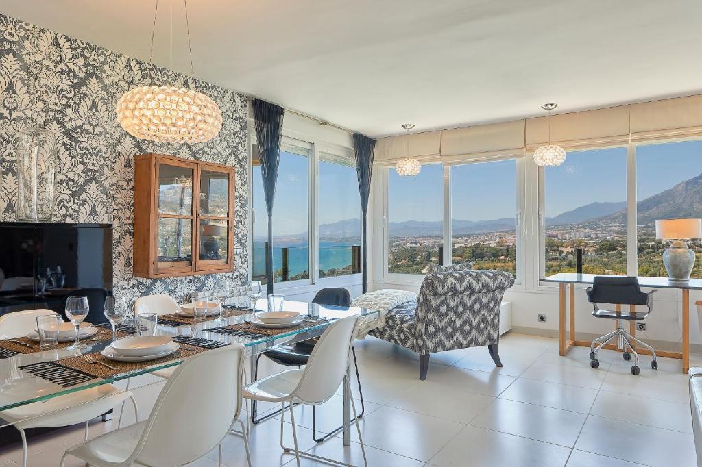 a dining room with a table and chairs and windows at Torre Real Vistas 360 cerca Trocadero Arena Marbella in Marbella
