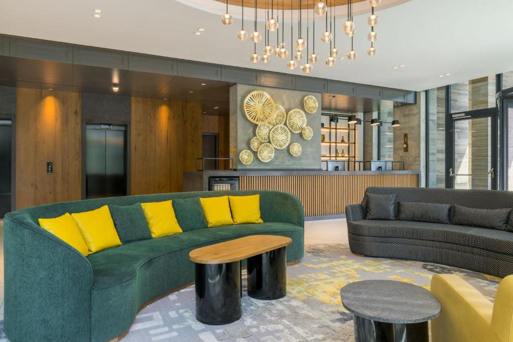 a living room with a green couch and yellow pillows at Four Points by Sheraton Budapest Danube in Budapest