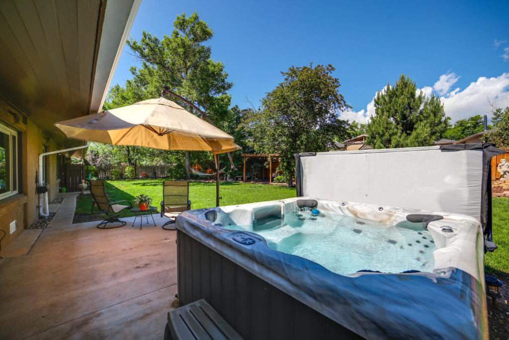 a hot tub on a patio with an umbrella at Broadmoor Getaway with Pickleball Court! in Colorado Springs