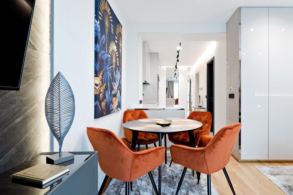 ein Esszimmer mit einem Tisch und orangefarbenen Stühlen in der Unterkunft Sunhill Residence 5* suite Castle district in Budapest