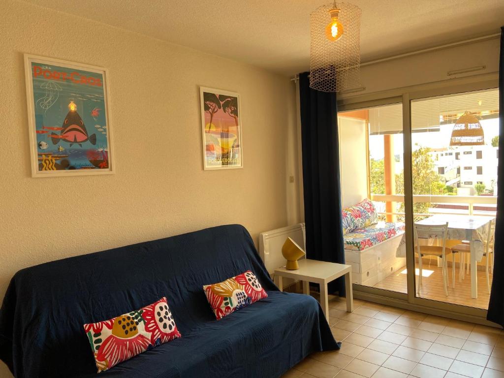 a living room with a blue couch and a balcony at Appartement La Favière in Bormes-les-Mimosas