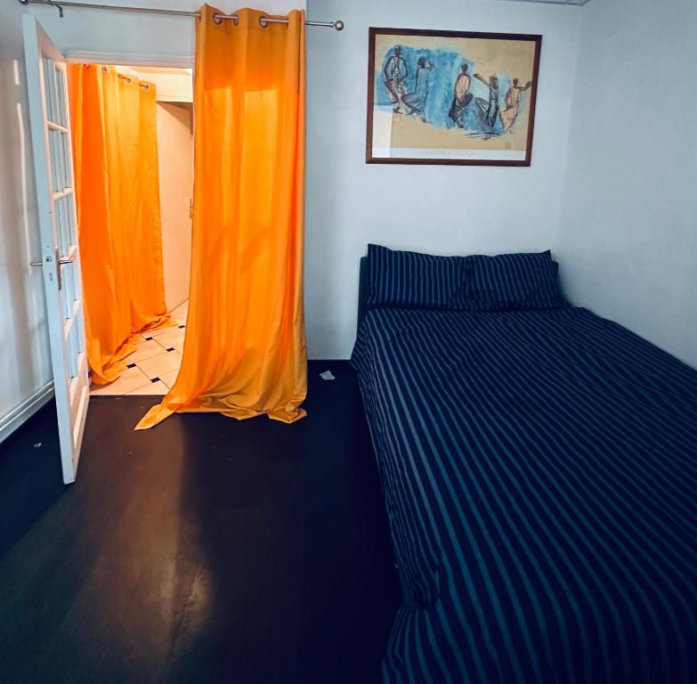 um quarto com 2 camas e uma cortina laranja em La pause em Saint-Maur-des-Fossés
