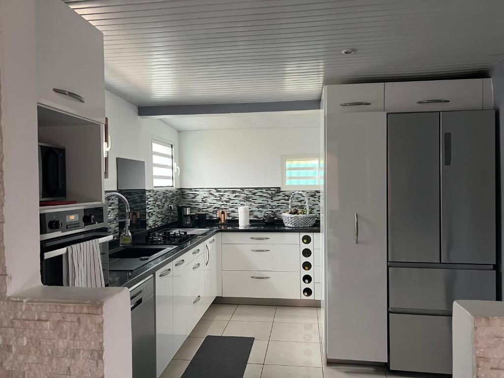 a kitchen with white cabinets and a white refrigerator at Charmante Villa, kaz’ AA.Liyah in Pointe-à-Pitre