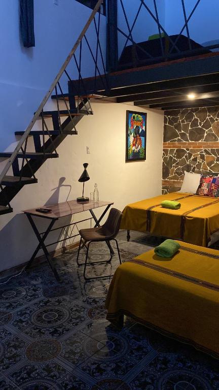 Zimmer mit 2 Betten, einem Tisch und einer Treppe in der Unterkunft Casa Santiago de los Caballeros in Antigua Guatemala