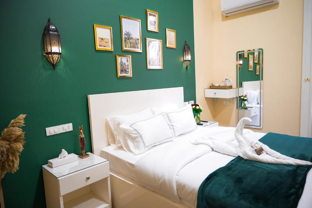 um quarto com uma cama branca e uma parede verde em Hathor House no Cairo