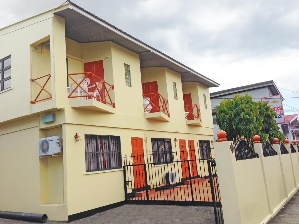 a yellow building with red doors and a fence at Sundeck Suites in Boissiere Village