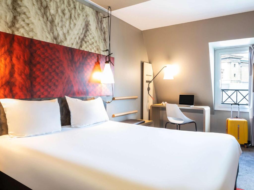 パリにあるイビス‐パリ‐ガールドゥノール ラファイエットの大きなベッドとデスクが備わるホテルルームです。