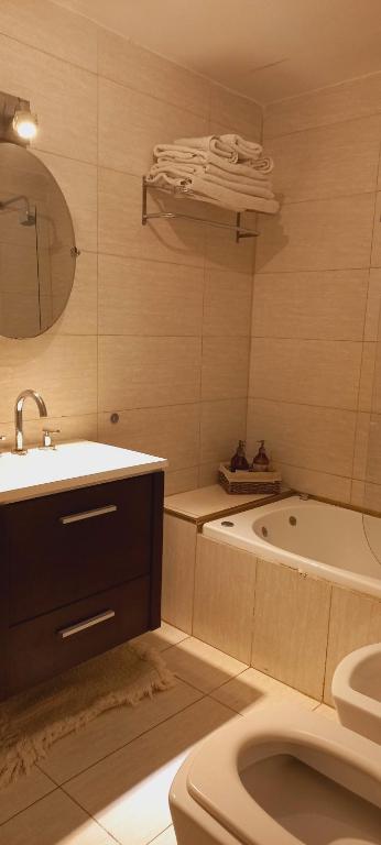 a bathroom with a sink and a tub and a toilet at La Pausa, Departamentos y Casas in Chacras de Coria