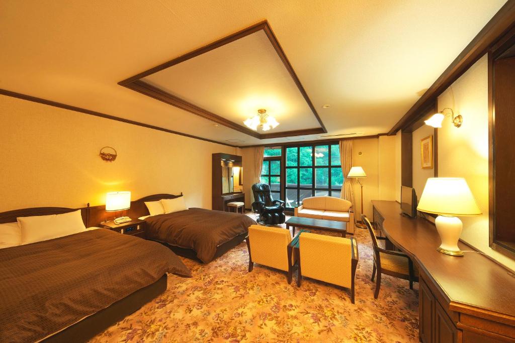 una camera d'albergo con 2 letti e una scrivania di Hotel Hotaka a Takayama