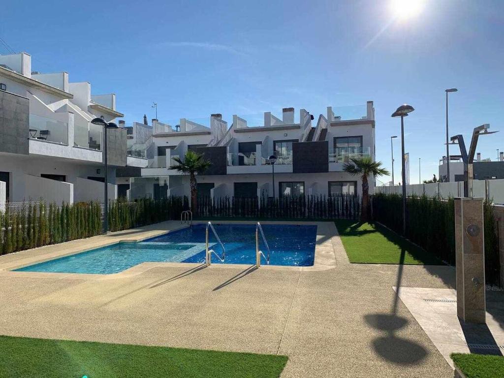 une maison avec une piscine en face d'un bâtiment dans l'établissement Hermoso estudio en Pilar de la Horadada, à Pilar de la Horadada