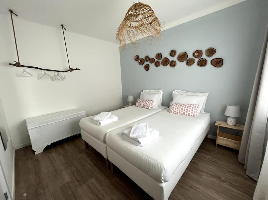 a white bedroom with a white bed with two pillows at Casa dos Avós in Vila Nova de Milfontes