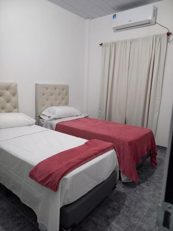 1 dormitorio con 2 camas y manta roja en Portal del Rio en Formosa