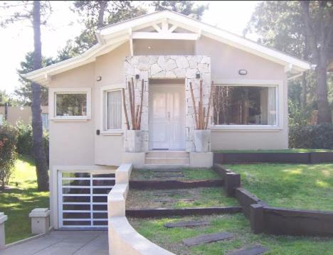una pequeña casa blanca con un patio de césped en Casa en Pinamar Alquiler en Pinamar
