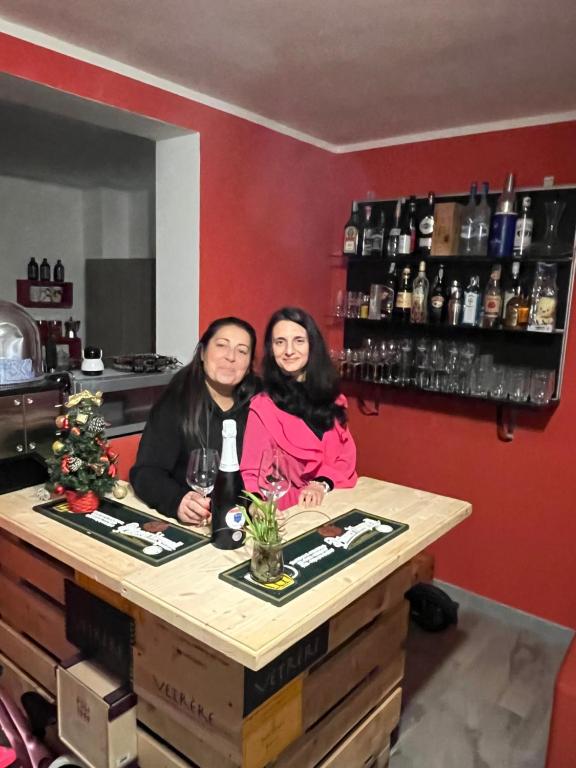 two women sitting at a bar with a bottle of wine at Casa Filippini in Bologna