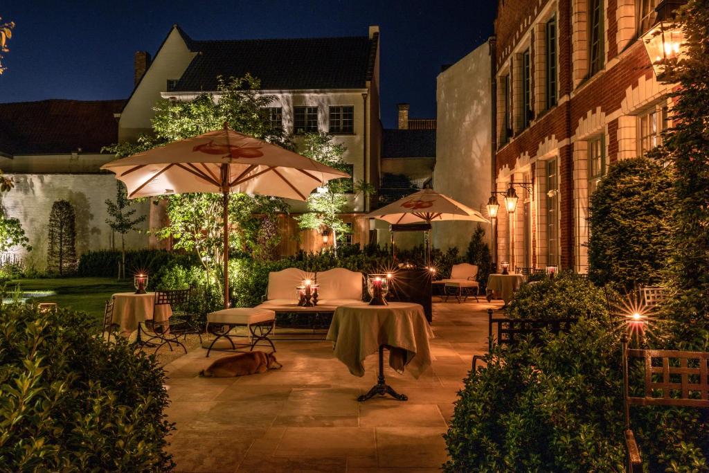 an outdoor patio with tables and umbrellas at night at The Notary in Bruges