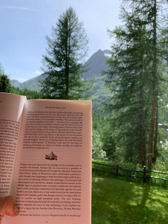 a person reading a book in front of a window at Casa Camas, wide 2bedroom, feel the mountain in Breuil-Cervinia