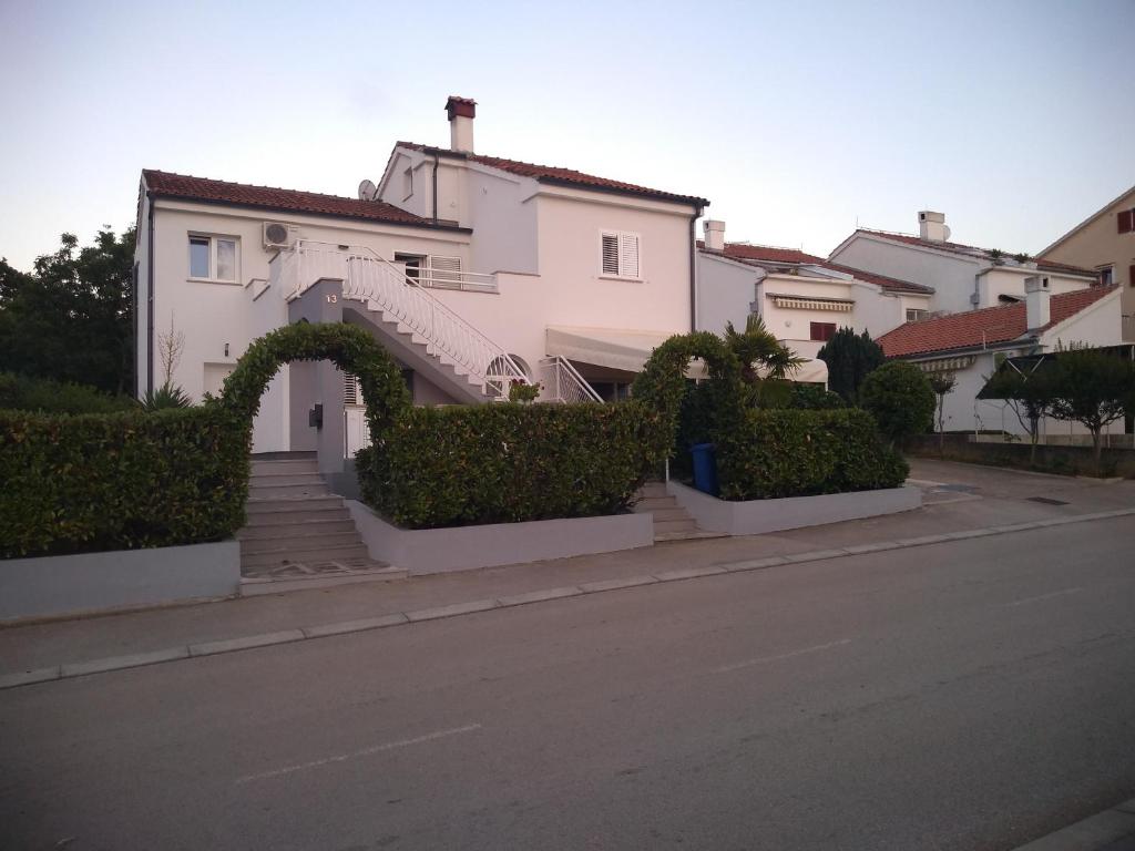 a white house with an arch on a street at Apartments with parking space Njivice, Krk - 14932 in Njivice